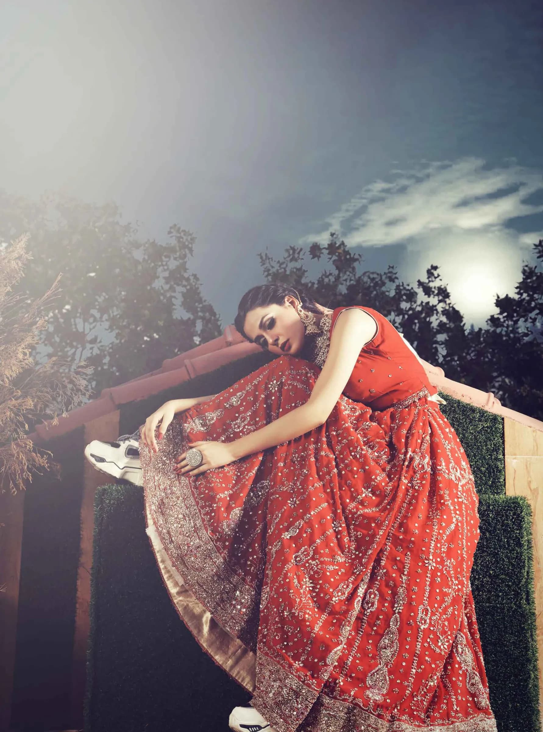 Model in a red printed dress reclining on steps at dusk