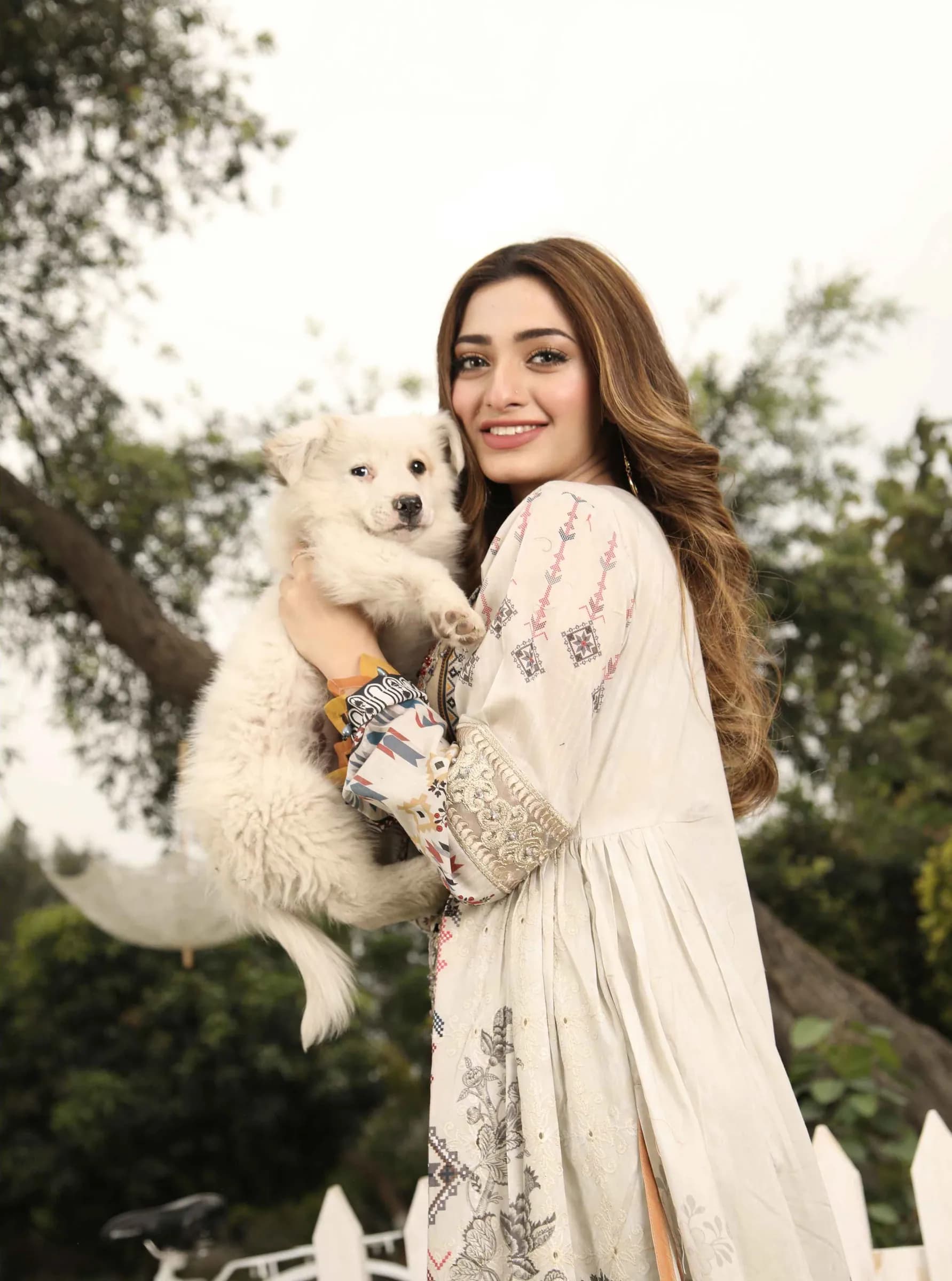 Model in white holding a small white dog