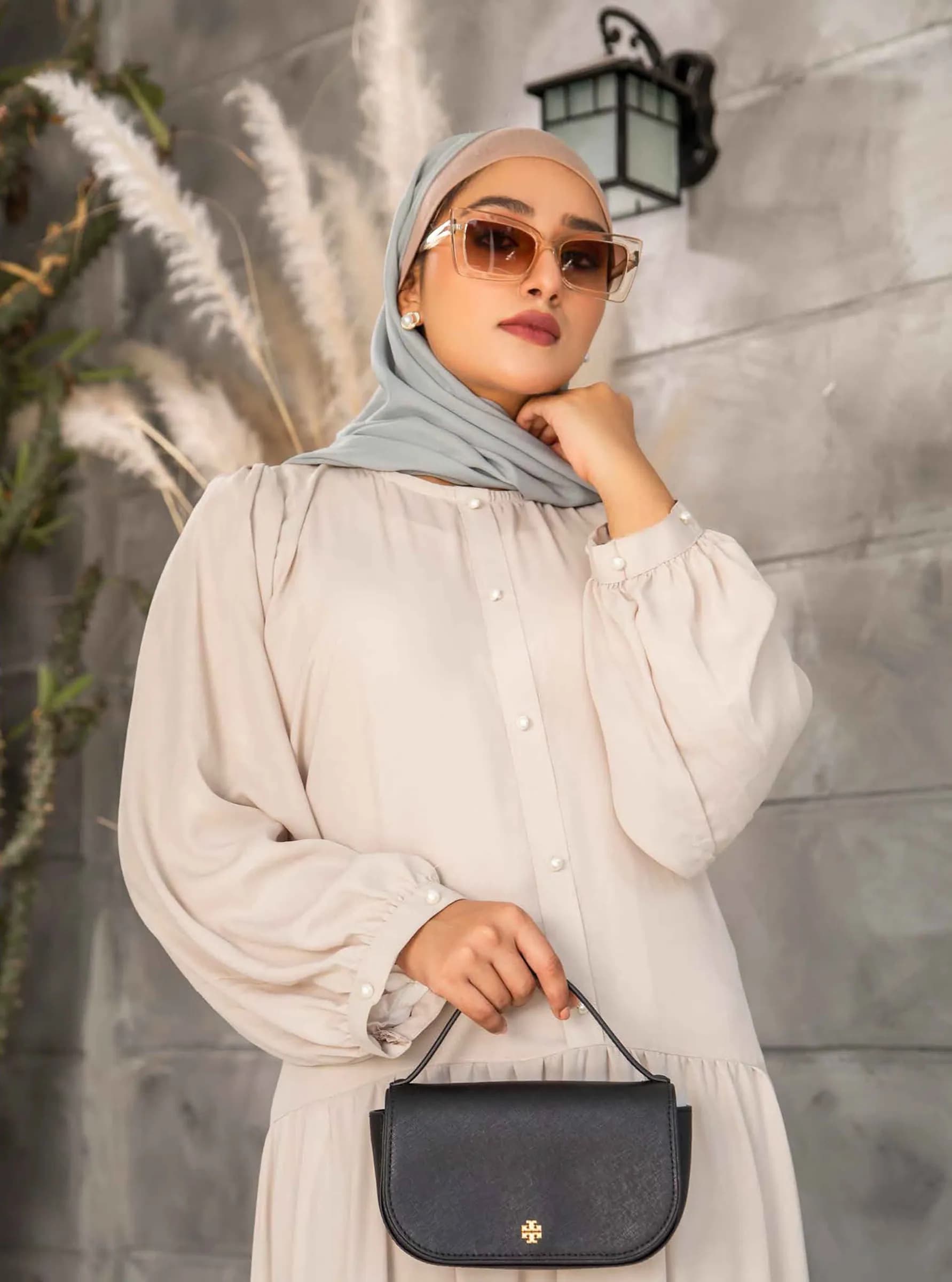 Model in white with sunglasses and a black handbag