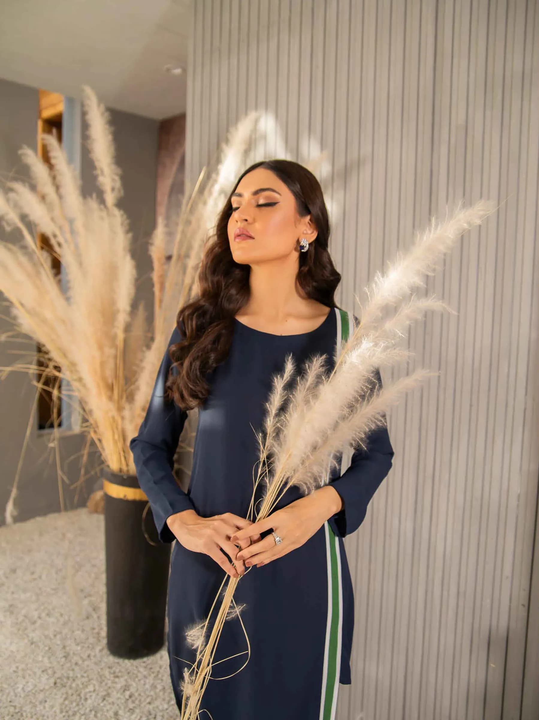 Model in navy beside dried pampas grass