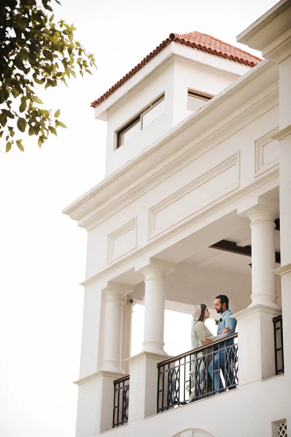 Couple on the balcony of a white colonial house