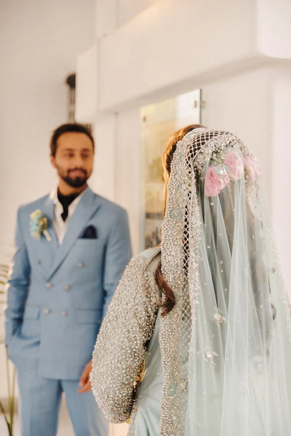 Groom in a blue suit beside the veiled bride