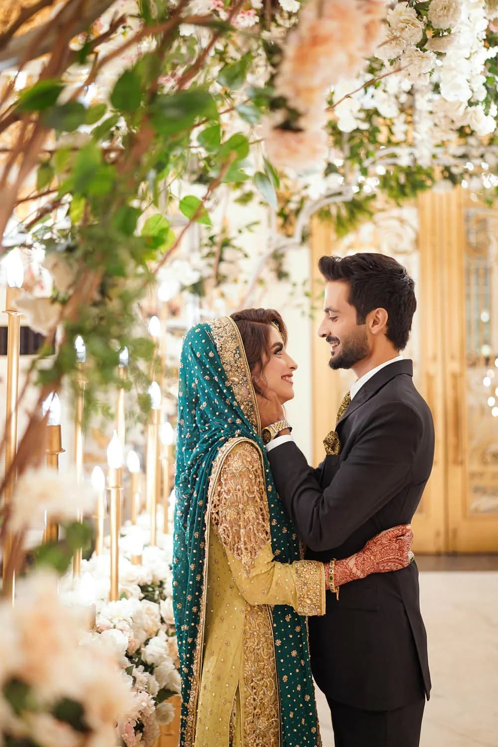 Couple in green and gold under a floral arch