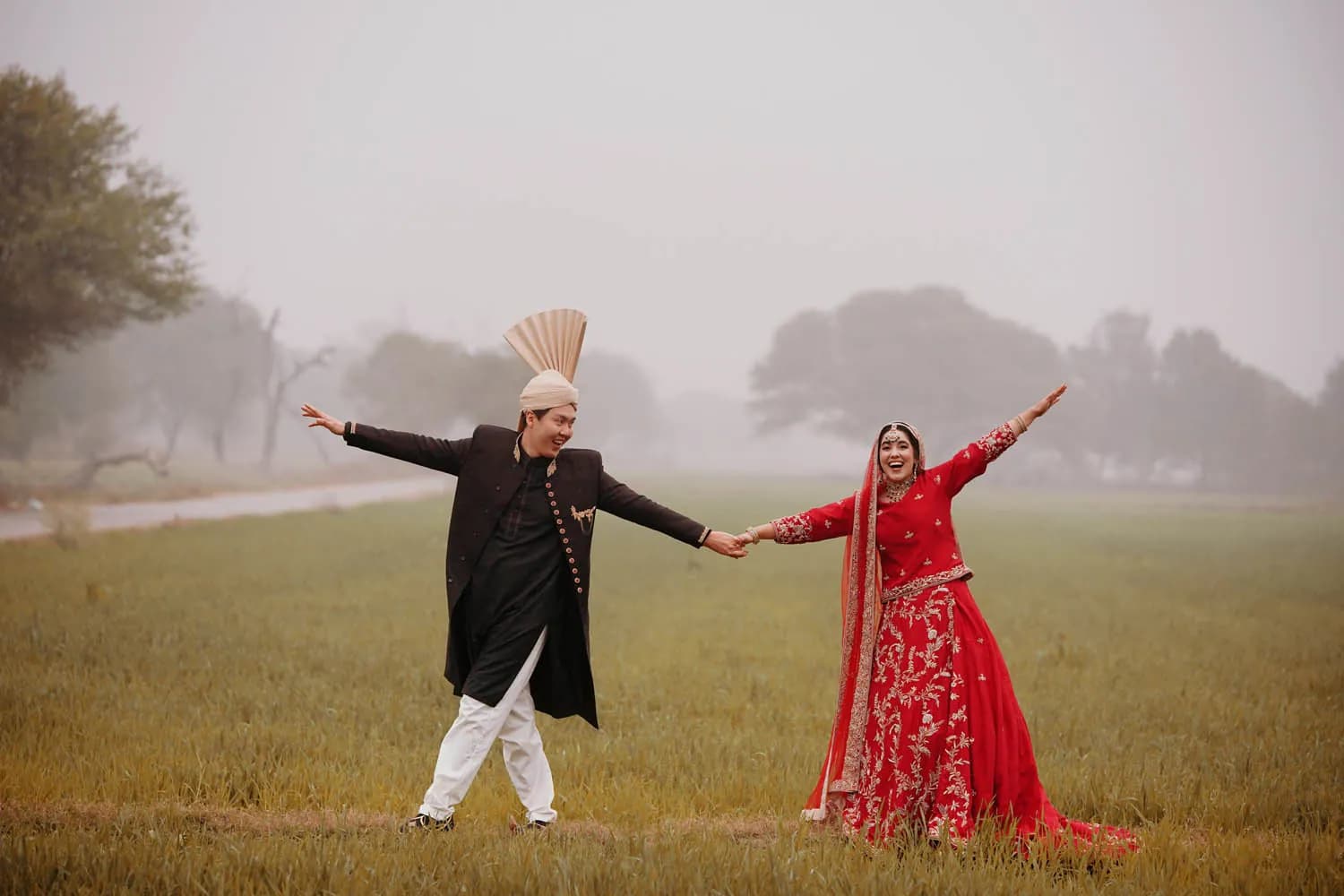 Couple dancing in a foggy field, the bride in red