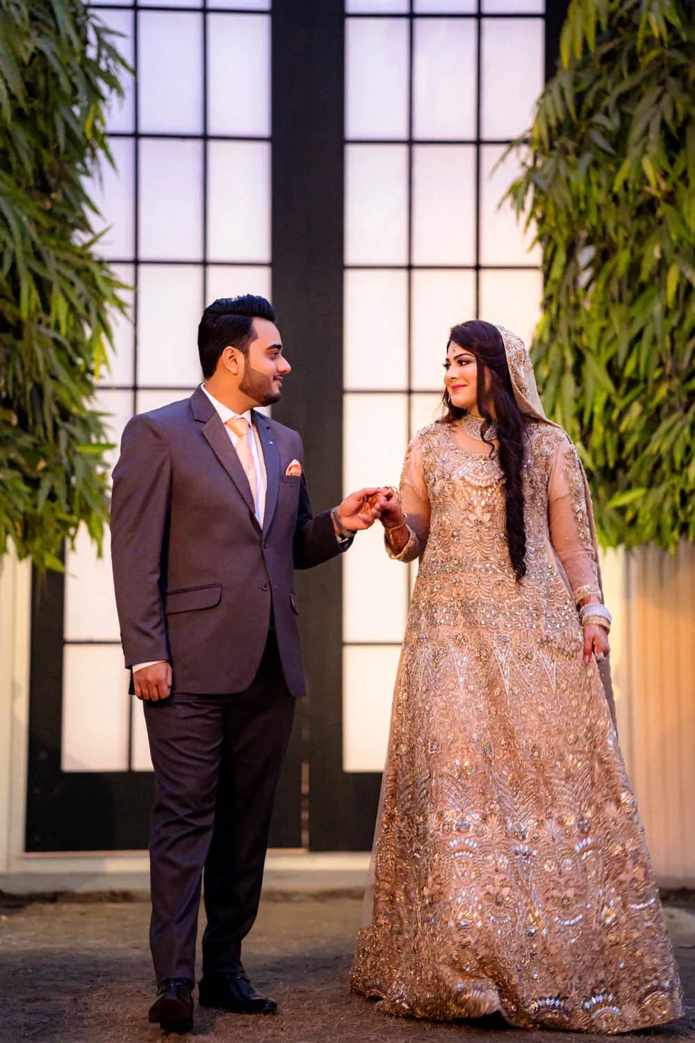 Couple holding hands before tall glass doors