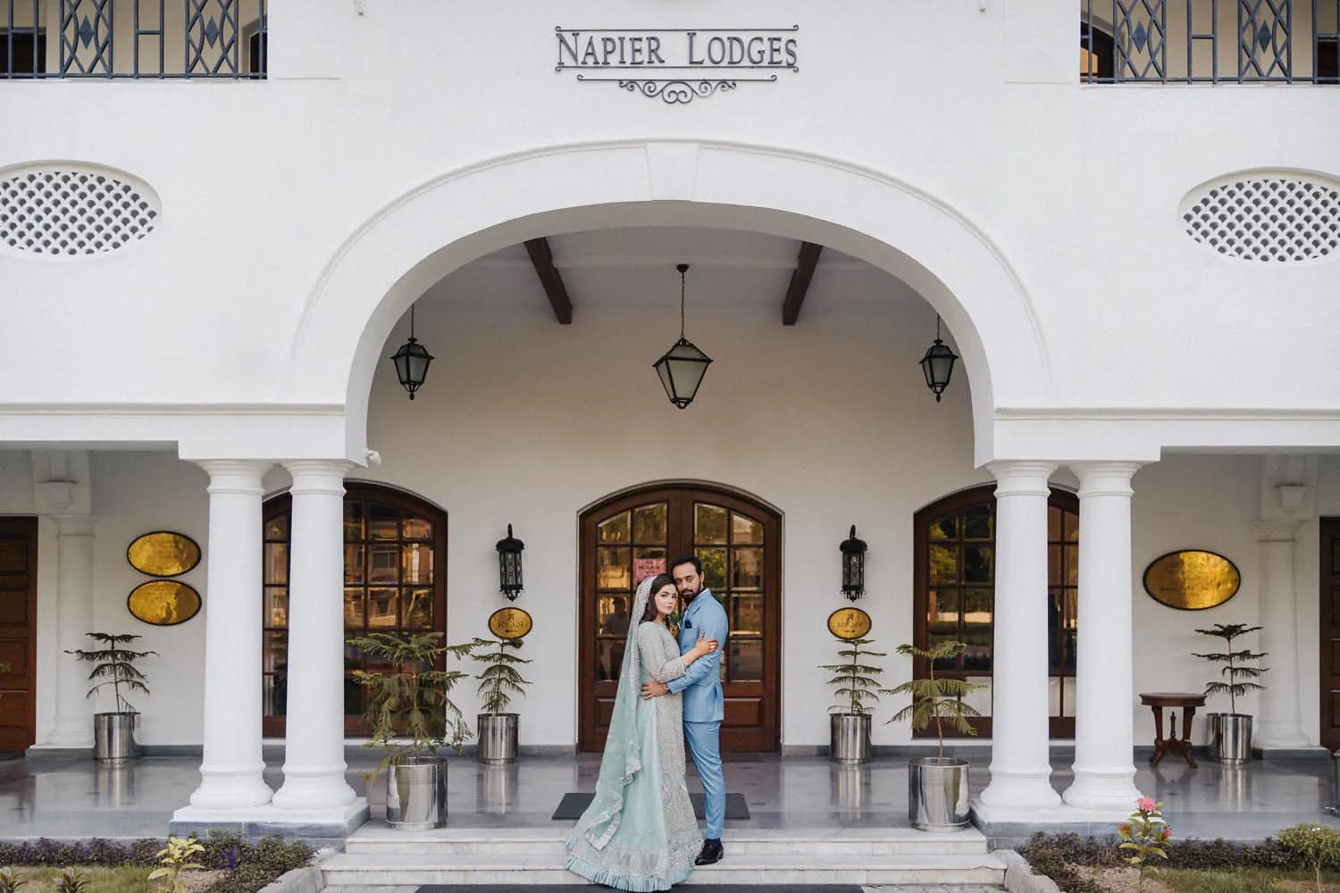 Couple in front of the white arches of Napier Lodge